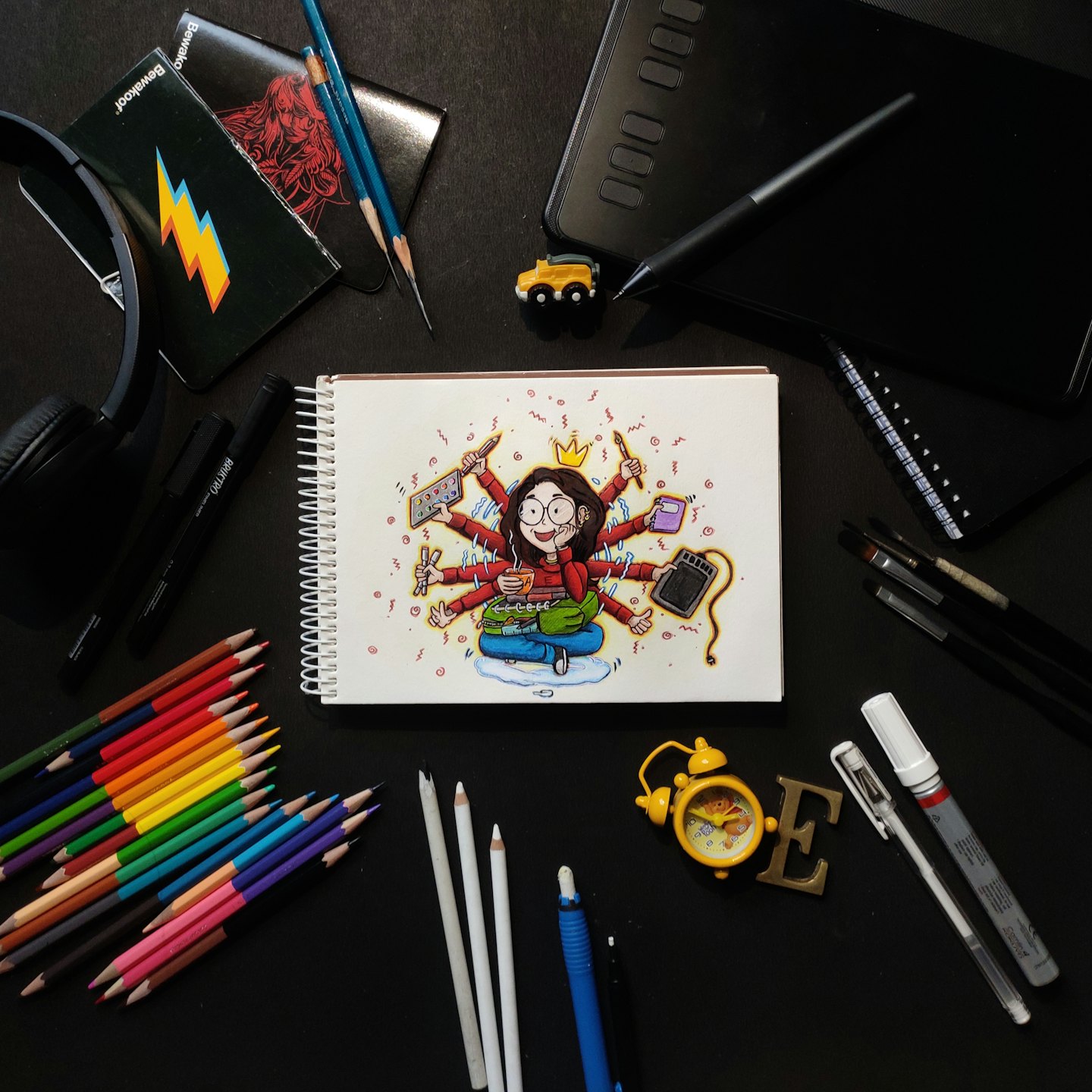 Materiali artistici e un album da disegno con l'illustrazione di una donna multitasking.